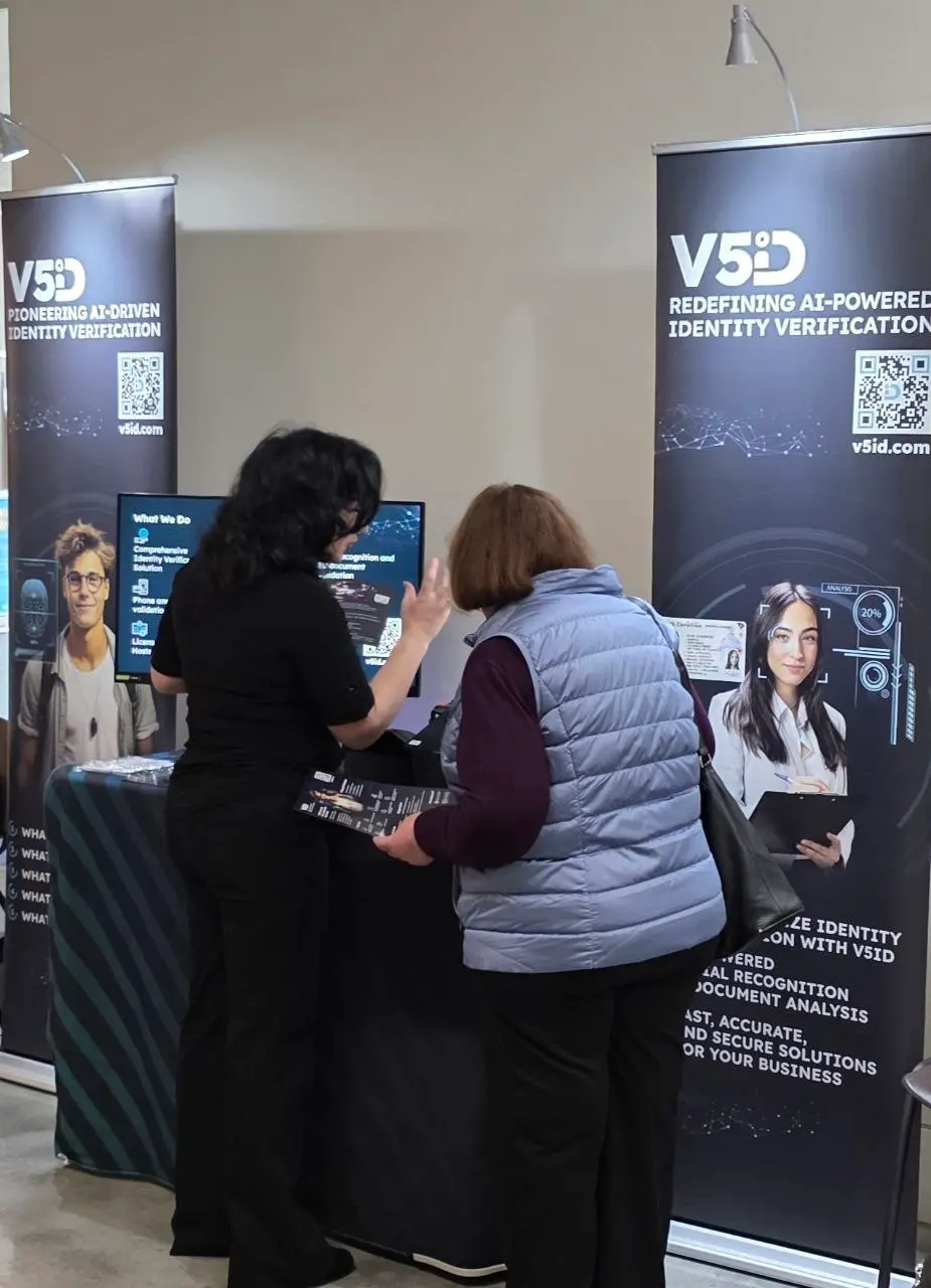 Explaining Kiosk Features at V5iD® Booth V5iD® CEO explaining identity verification kiosk features to attendee