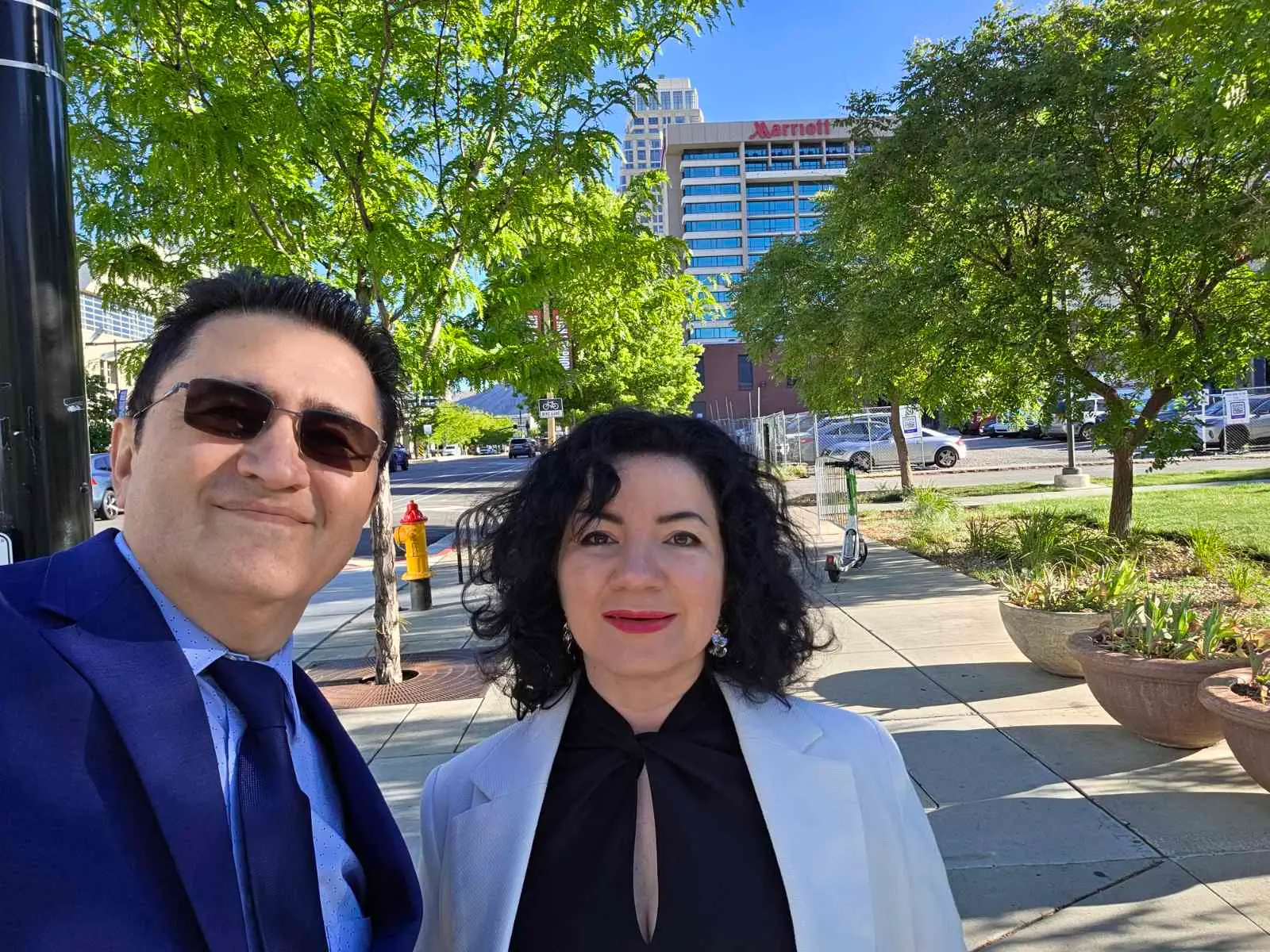 V5iD® CTO and CEO posing in a selfie on a sunny sidewalk in front of the Marriott hotel in Salt Lake City, where they will attend the SymWest conference from May 6-8, 2026.