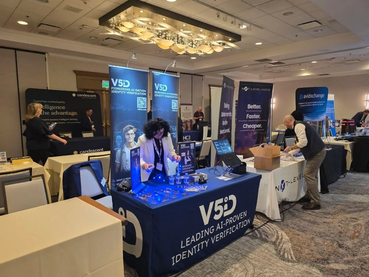 V5iD® CEO arranging swag and tech displays at the company's branded booth in the exhibit hall, making final preparations before the SymWest conference starts and visitors arrive