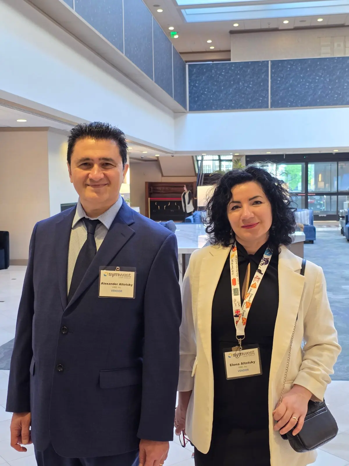 V5iD® CTO and CEO standing side-by-side in the Marriott hotel lobby, wearing their SymWest vendor badges before heading to the conference