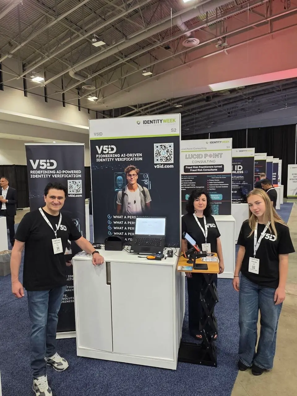 V5iD team members posing in front of their AI-powered identity verification booth and banners at Identity Week America 2026 exhibition hall