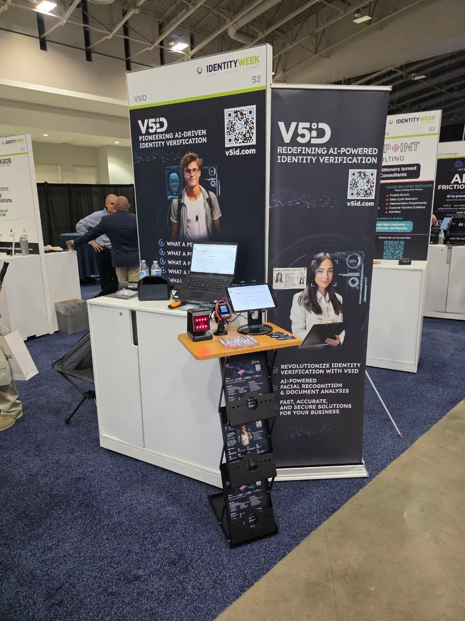 Fully set V5iD booth at Identity Week America 2026 featuring large banners, laptop demo station, document scanners, brochure stand and AI facial recognition messaging