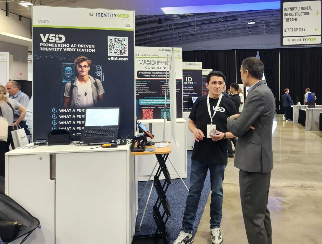 V5iD team member in conversation with a visitor next to the pioneering AI-driven identity verification display at Identity Week America 2026
