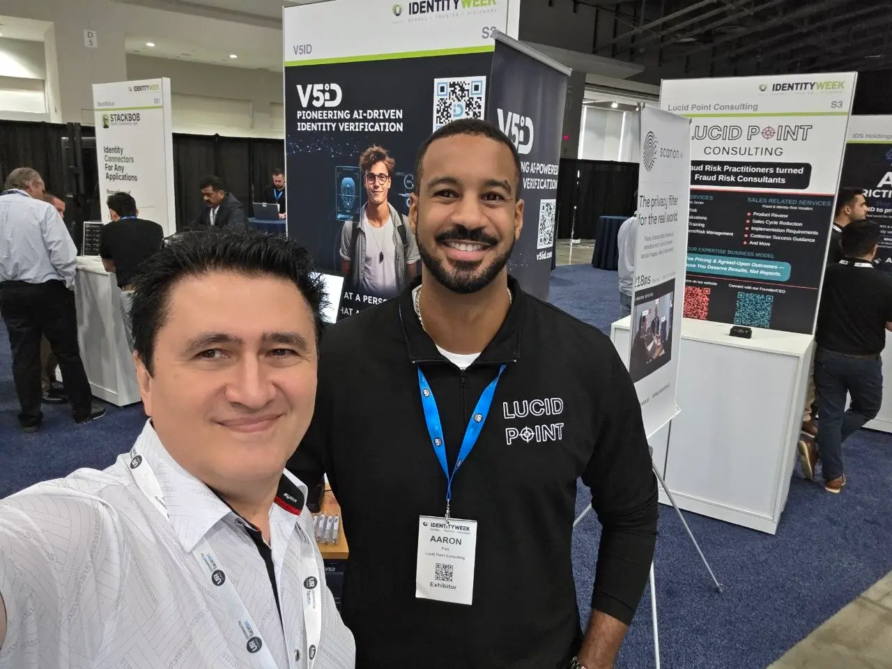 Friendly selfie of a V5iD representative with Aaron from Lucid Point Consulting in front of the V5iD AI identity verification booth at Identity Week America 2026