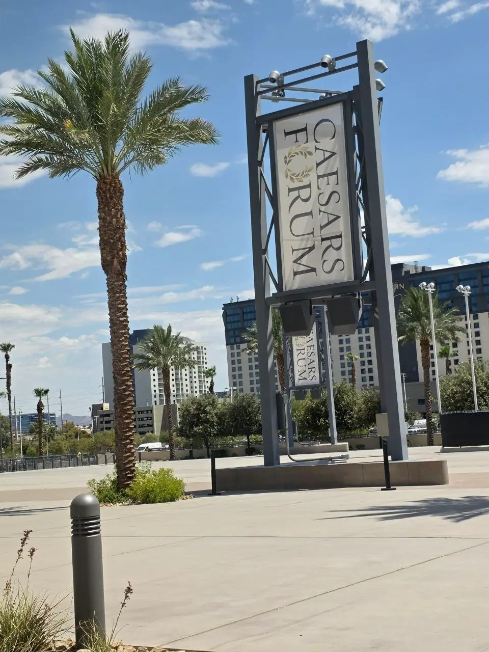 Caesars Forum entrance sign, Las Vegas Tall outdoor sign reading “Caesars Forum” at the venue entrance in Las Vegas, with palm trees, modern buildings, and a clear blue sky in the background.