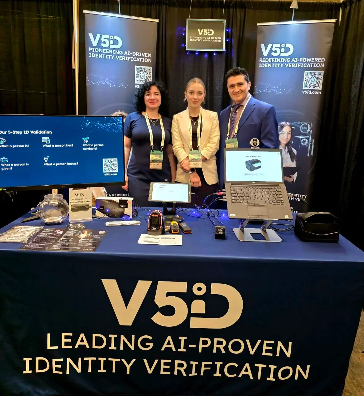 V5iD Team at 2026 Quad-State Bankers Convention V5iD team presenting AI-driven identity verification technology at the 2026 Quad-State Bankers Convention. Three professionals stand behind a branded booth featuring banners, a large monitor, laptop, and various verification devices.
